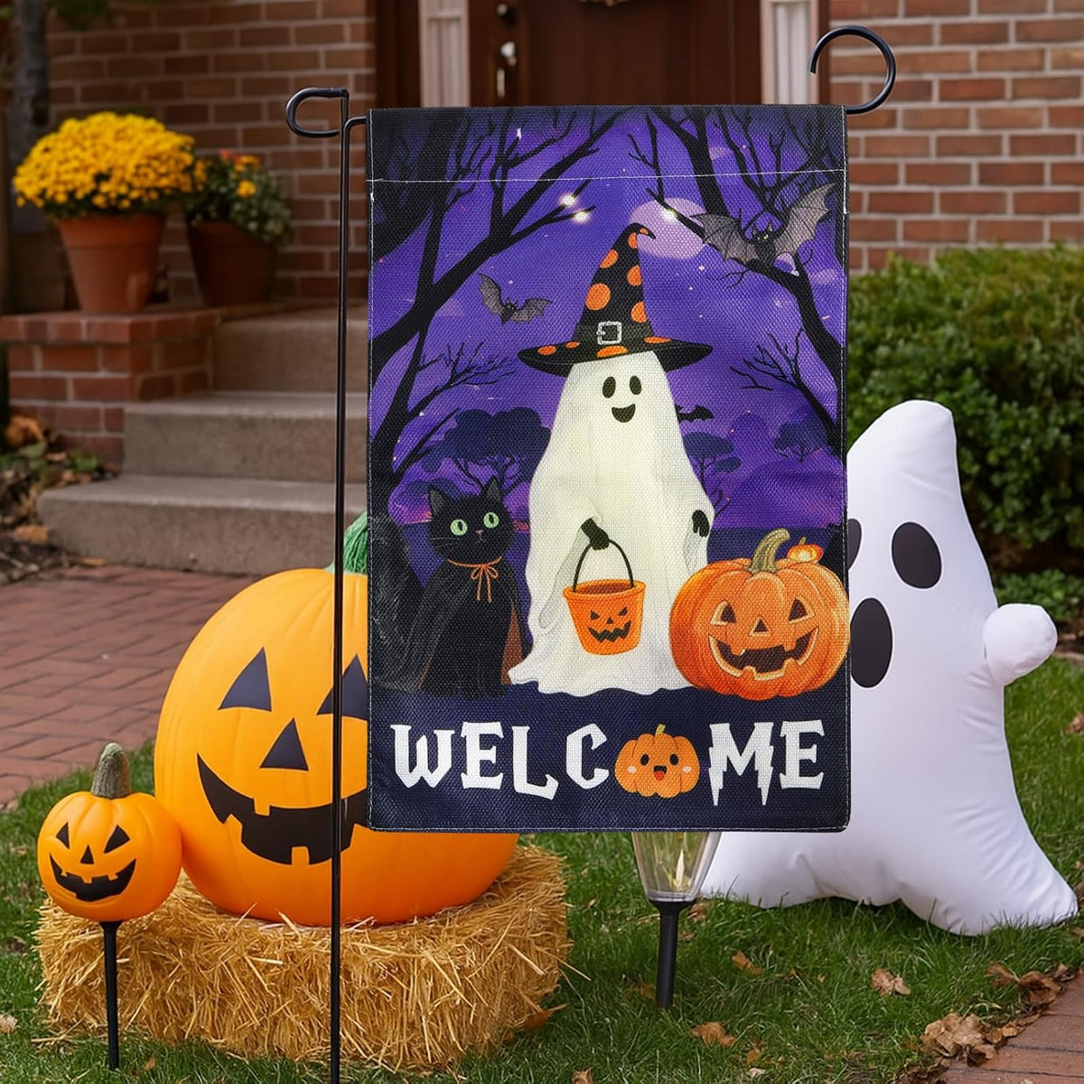 Halloween welcome flag beside jack-o'-lantern and inflatable ghost